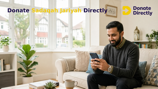 British Muslim man donating to a water well charity from his living room as Sadaqah Jariyah.