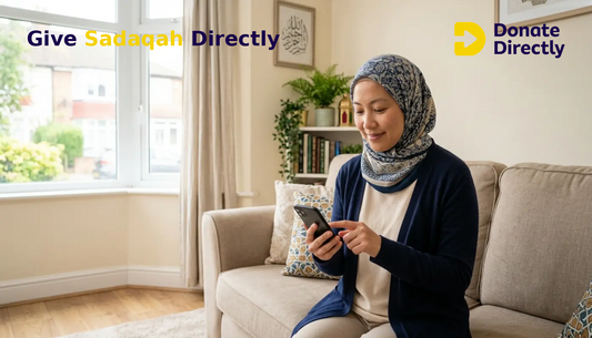 Muslim woman in a UK home donating sadaqah on her phone with a calm, hopeful expression