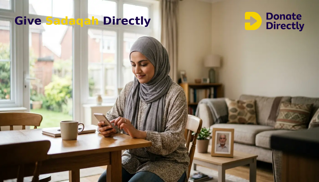 UK Muslim woman giving sadaqah on her phone at home with a framed photo of a loved one nearby