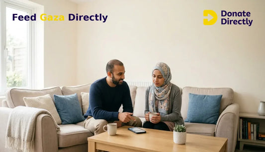 British Muslim couple at home deciding to donate to Gaza using a smartphone in a bright living room.